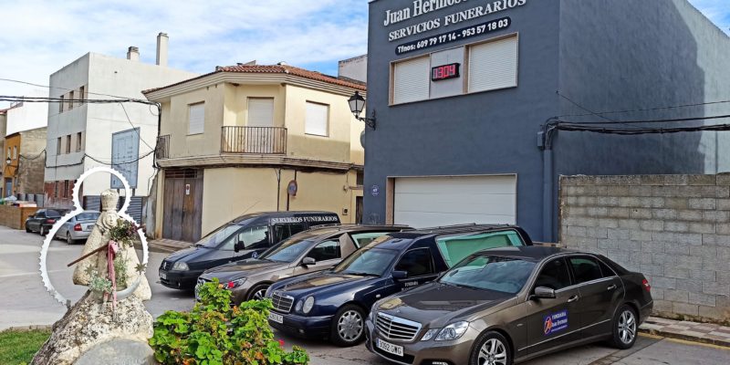 Fachada de la Funeraria Juan Hermoso E Hijos junto con los vehículos de la empresa y la imagen de la Virgen de la Cabeza en Torredonjimeno